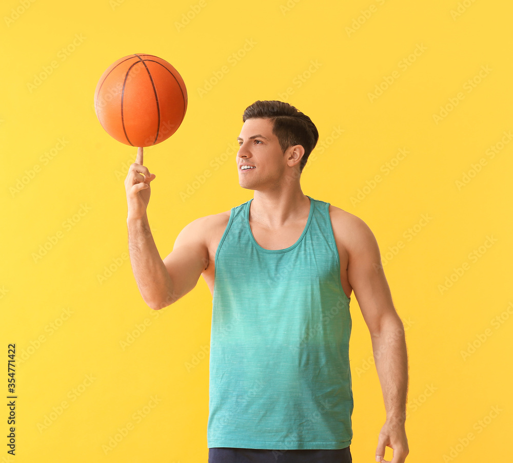 Sporty young man with ball on color background