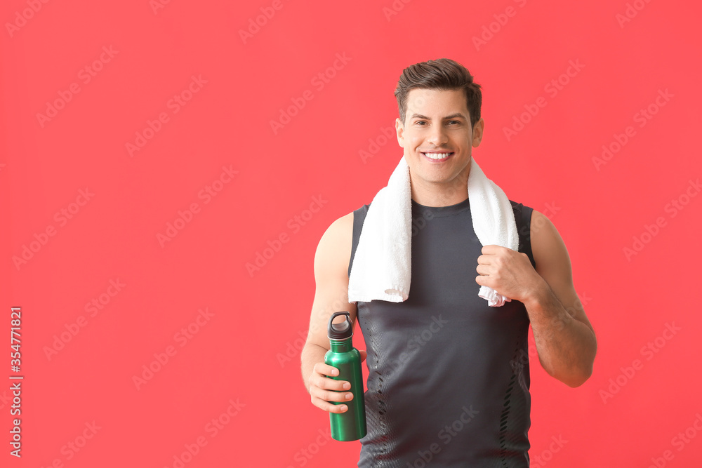 Sporty young man with water on color background