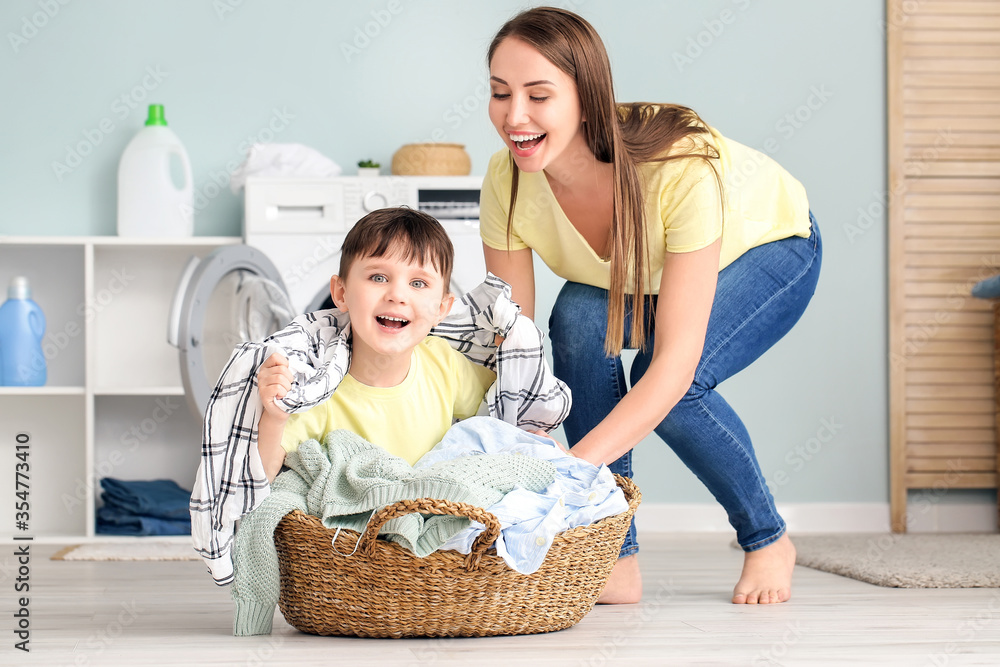 Young woman with her little son having fun while doing laundry at home