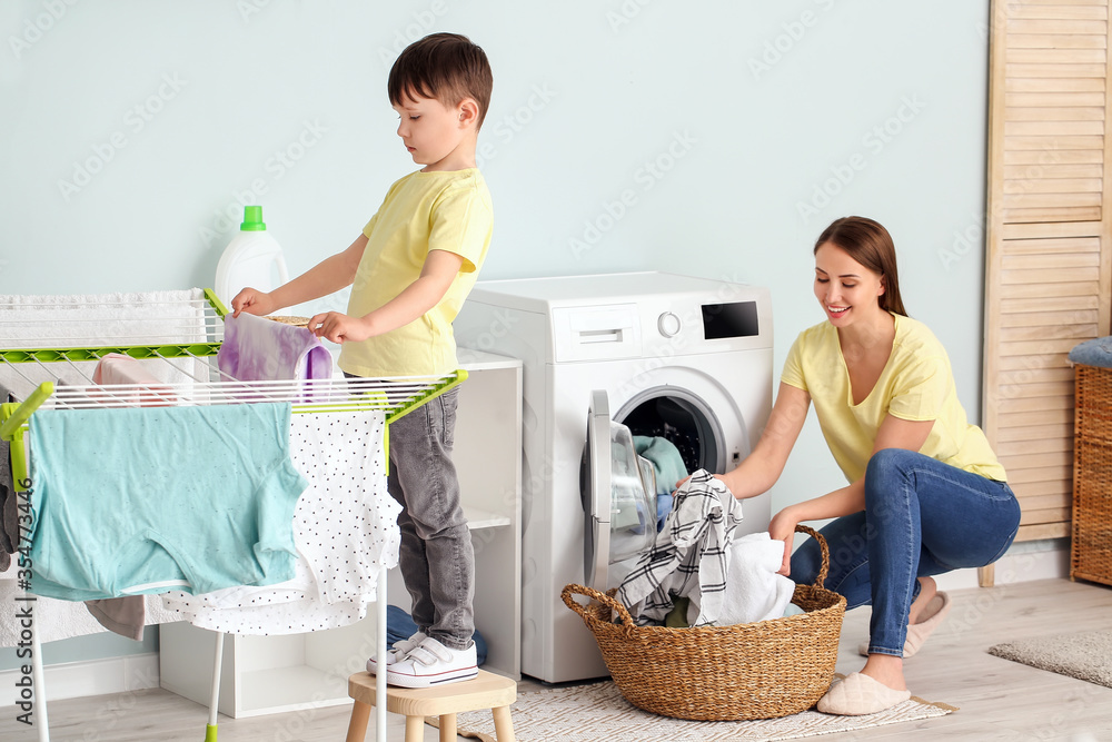 Young woman with her little son doing laundry at home