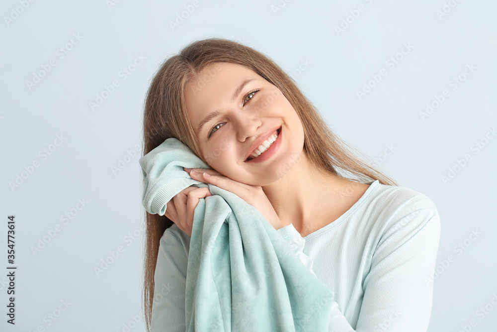 Young woman with clean laundry on color background