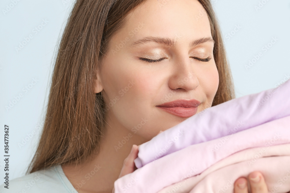 Young woman with clean laundry on color background