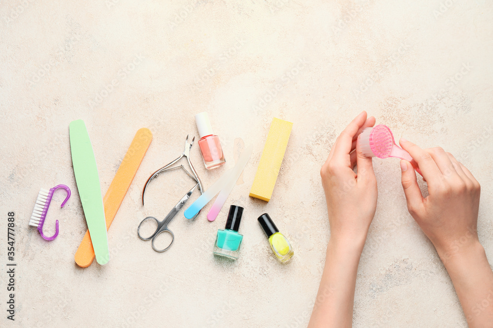 Female hands with supplies for manicure on light background