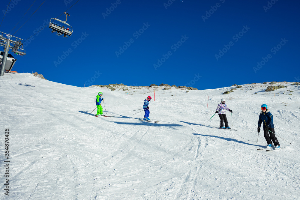 四个孩子一个接一个地在高山斜坡上滑雪