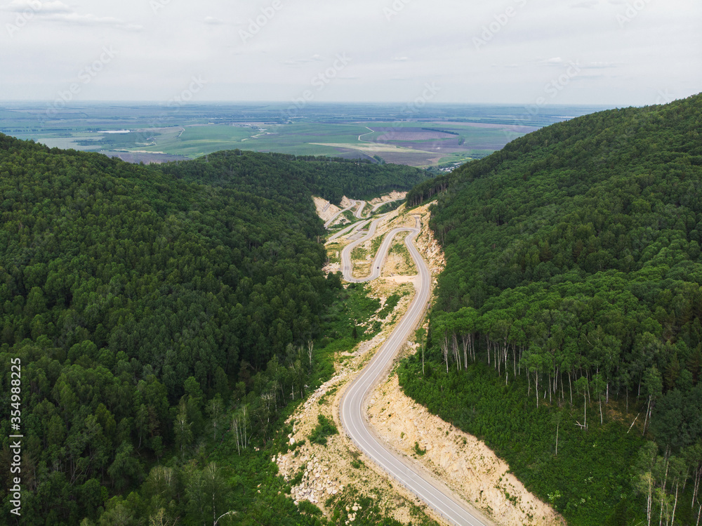 Aerial top vew of winding road in the mountains, drone shot. Altai Krai, Western Siberia, Russia. Ro