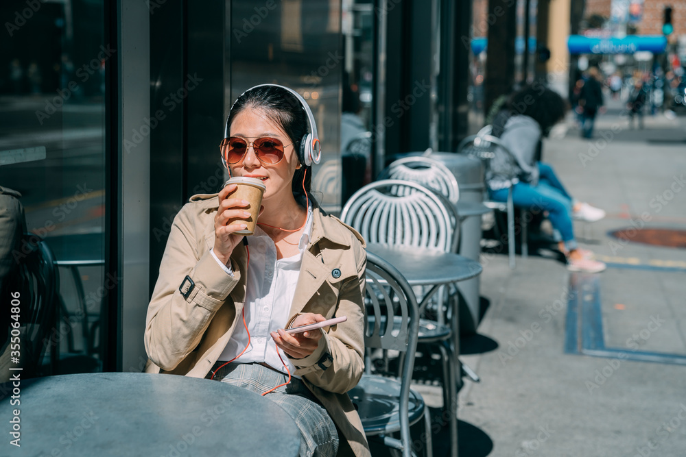 Pretty woman relax outdoors street coffee shop sit at table listen music in headphones and using mob