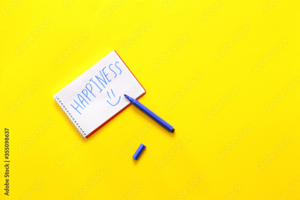 Notebook with word HAPPINESS and marker on color background