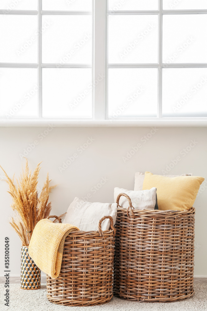 Wicker baskets with pillows and plaid in room