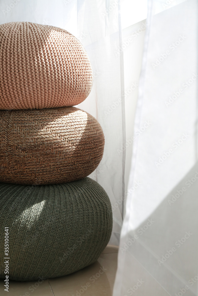 Stylish poufs near window in room