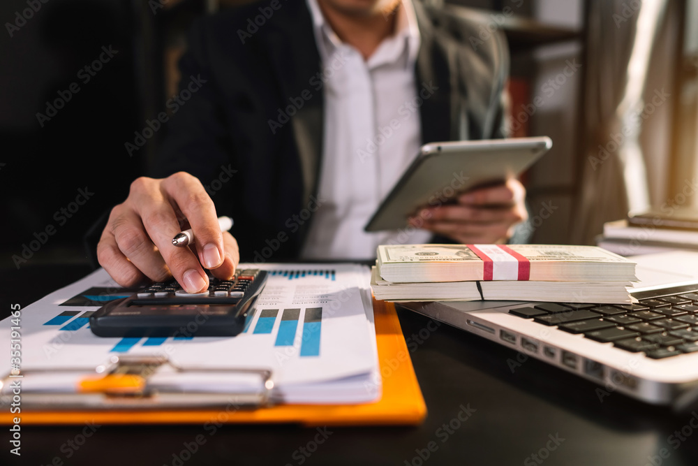 
Businessman hands working with finances about cost and calculator and laptop with tablet, smartphon