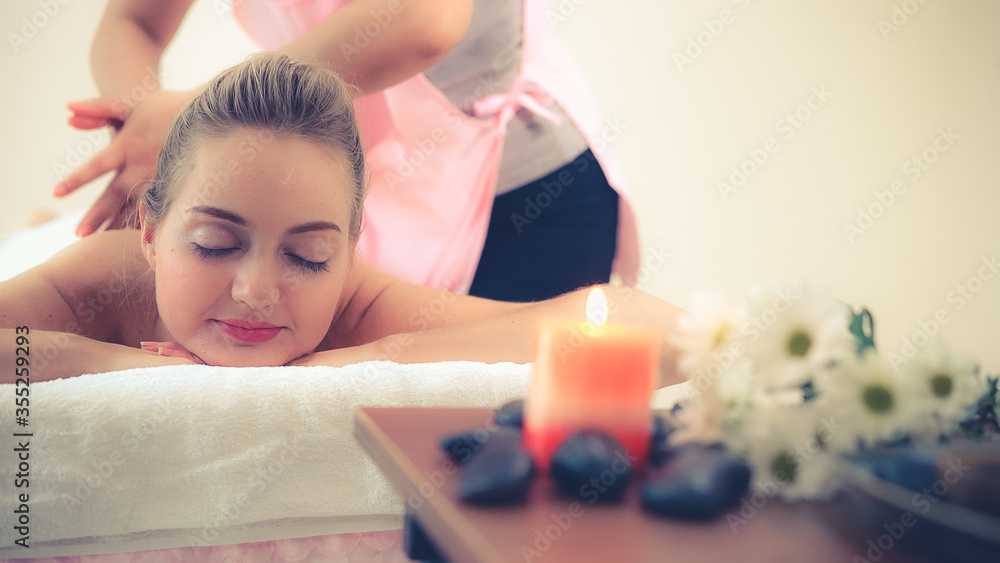 Relaxed woman getting back massage in luxury spa with professional massage therapist. Wellness, heal