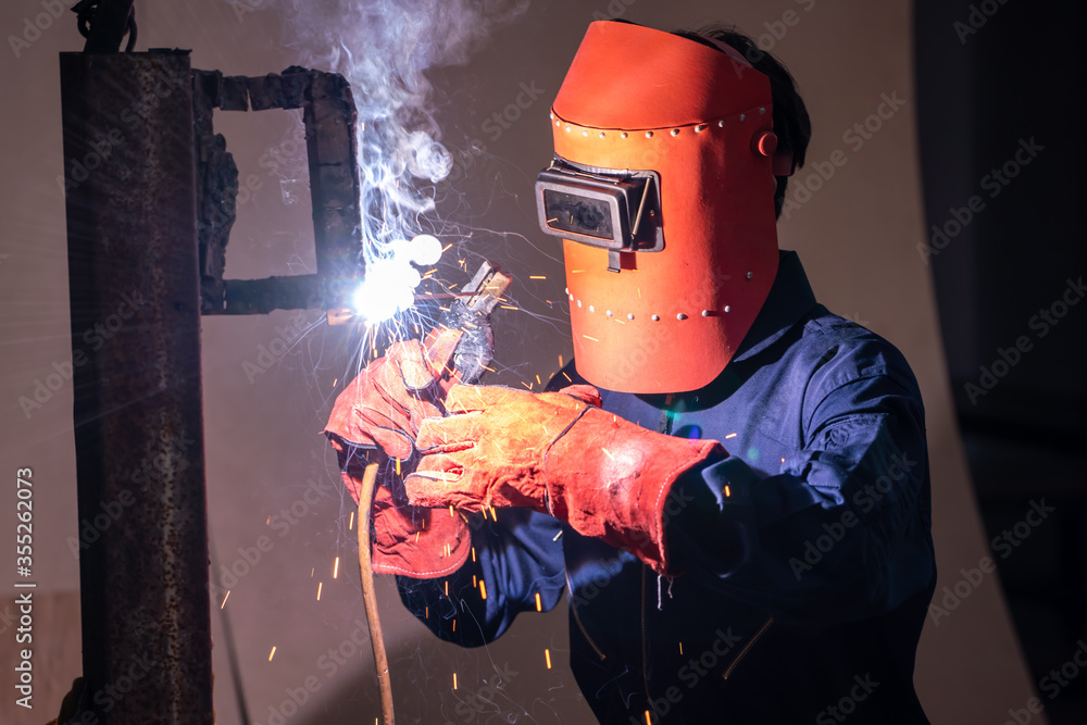 Metal welding steel works using electric arc welding machine to weld steel at factory. Metalwork man