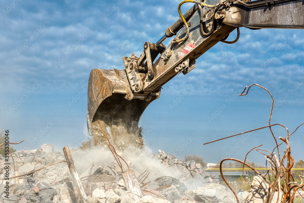 An excavator spills soil out of a bucket.