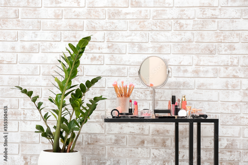 Table with set of decorative cosmetics in room