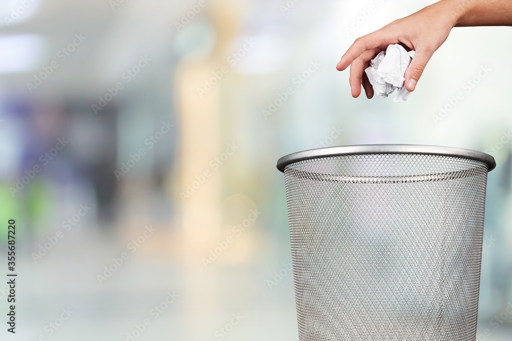 Hand throwing out paper into the trash basket