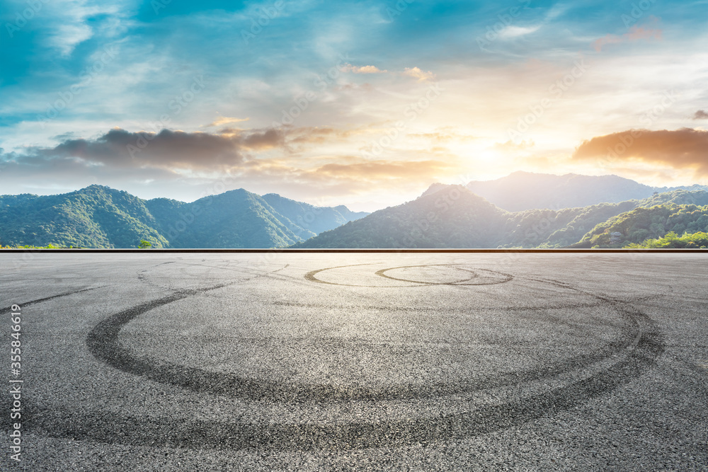 空旷的赛道道路和日落时的青山自然风光。