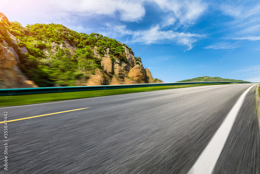 Motion blurred asphalt road and mountain natural landscape on a sunny day.