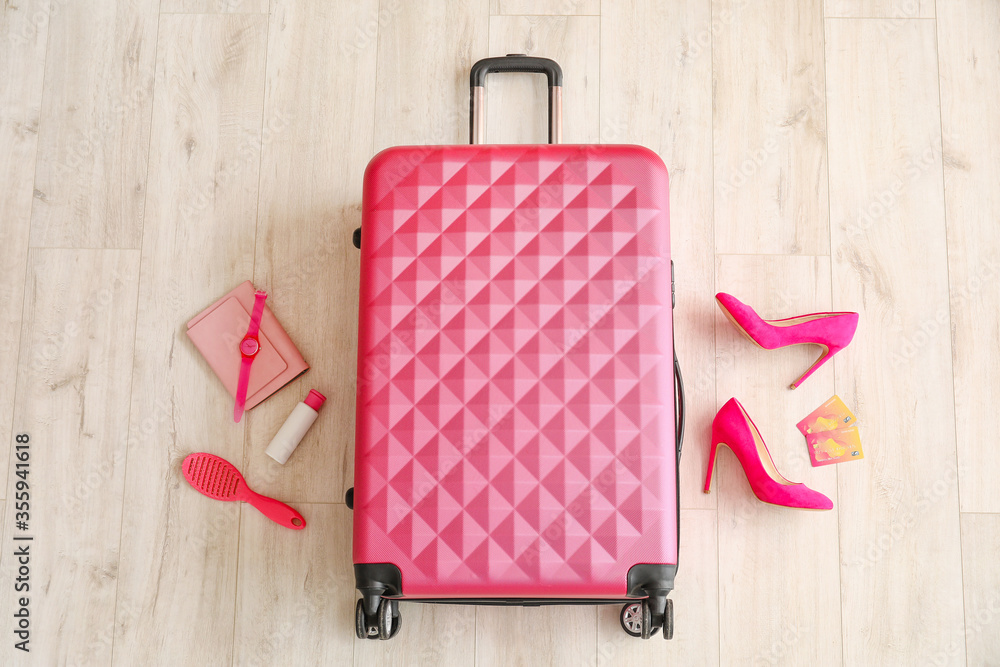 Packed suitcase and accessories on wooden background