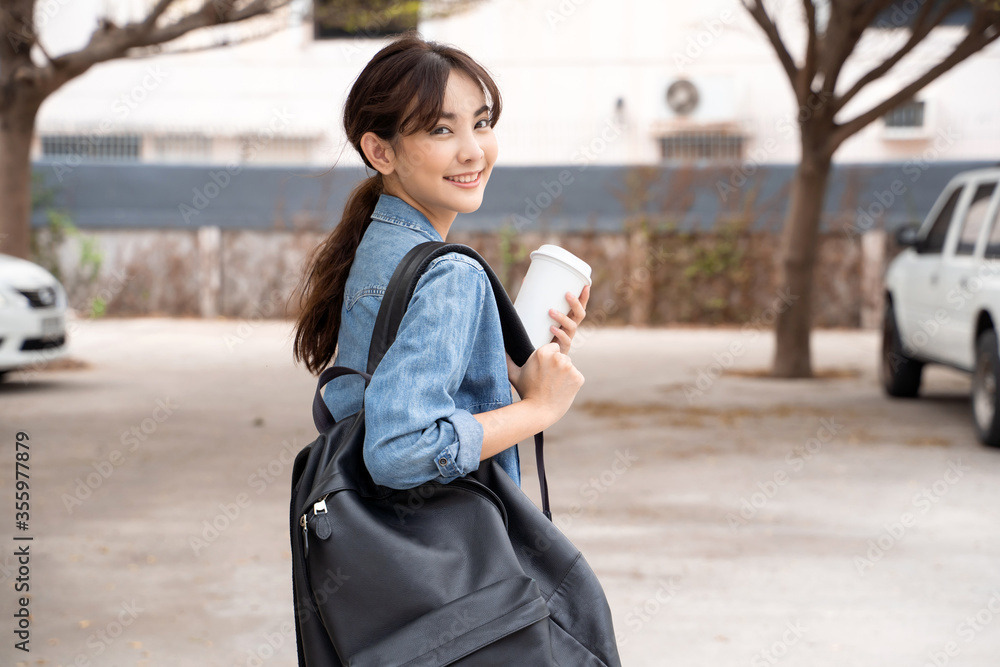 年轻的亚洲女学生拿着咖啡和背包的肖像