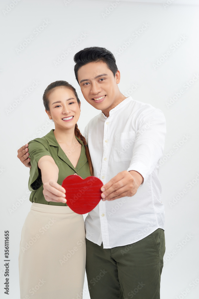 Loving young couple standing in embrace and holding heart shape isolated on white background