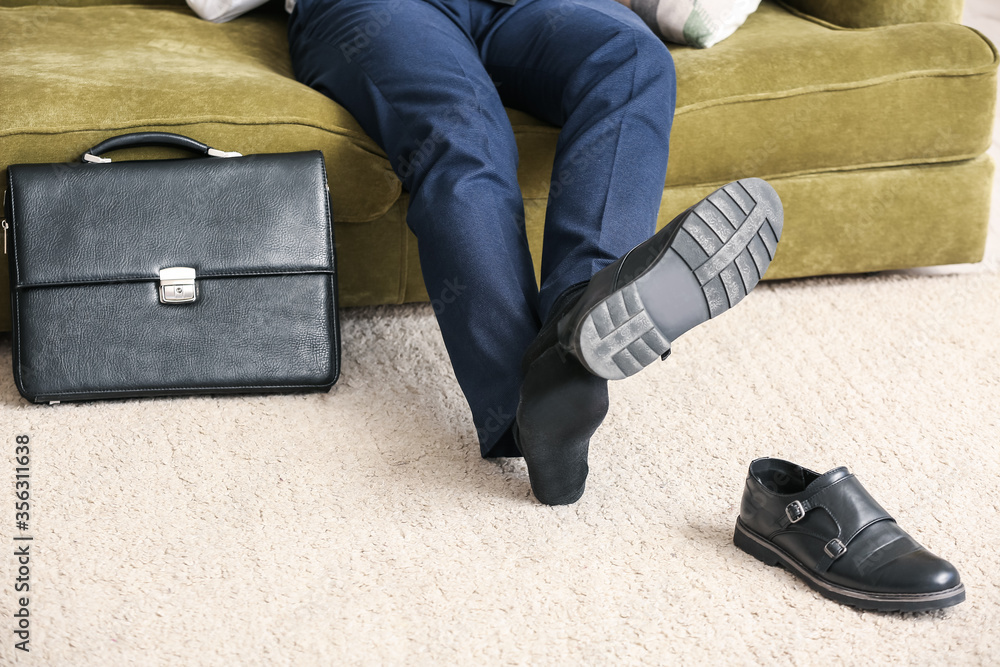 Businessman taking off his shoes at home after long working day