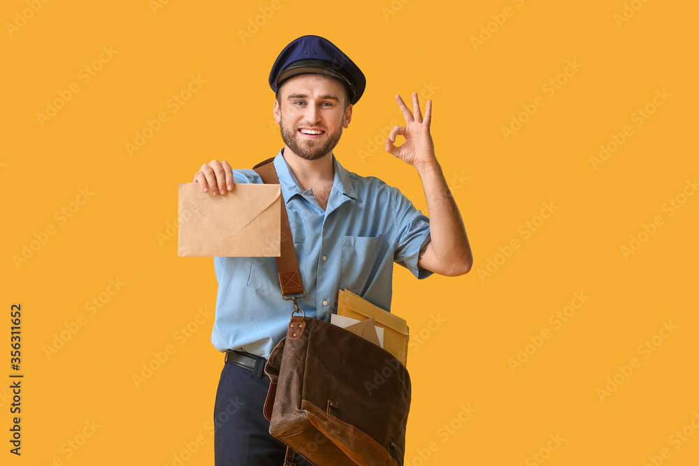 Handsome young postman on color background