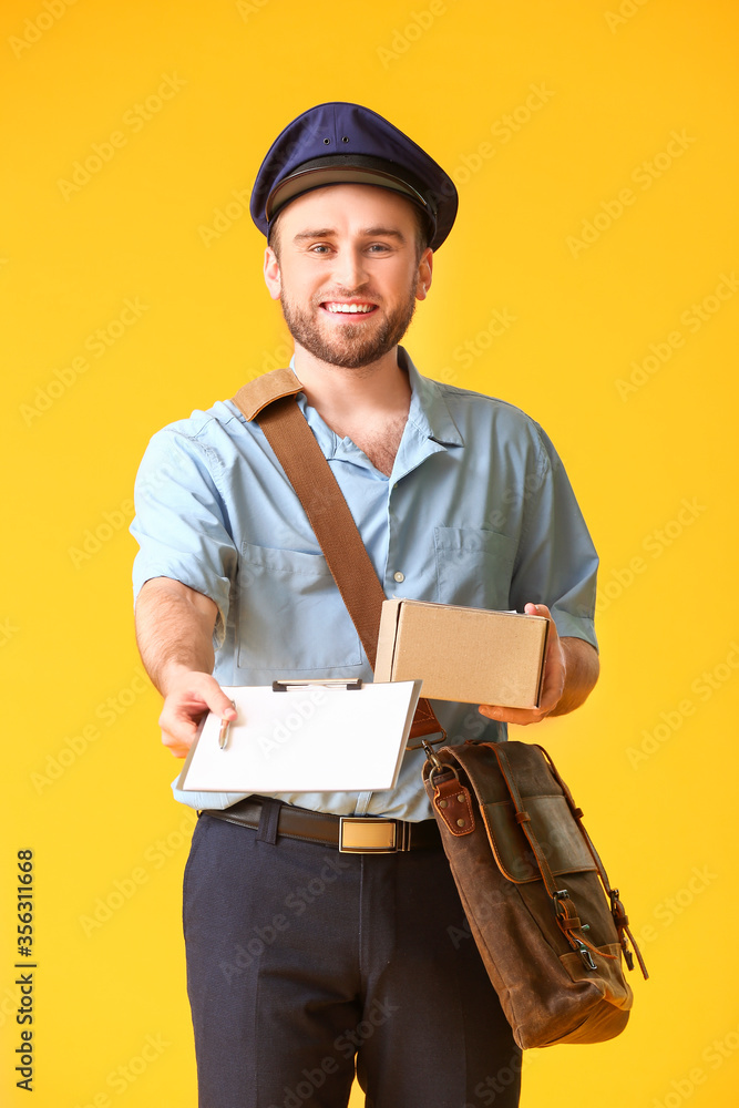 Handsome young postman on color background