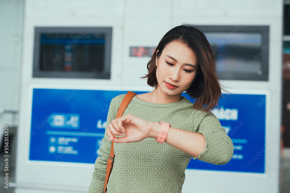 美丽的女人看着机场等飞机的时钟