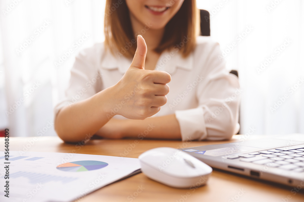 Business person working in office giving thumbs up for her archievement on her job