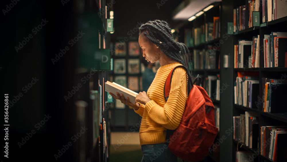 大学图书馆：天才美丽黑人女孩的肖像站在一排排书架和S之间