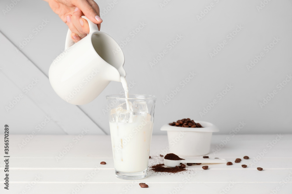 Woman preparing tasty dalgona coffee on table