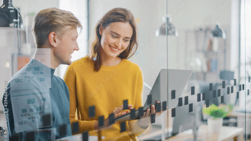 Portrait of Beautiful Young Woman Shows Laptop Display to Her handsome Male Colleague, Working on Ne