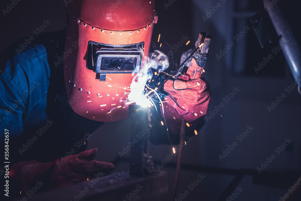 Metal welding steel works using electric arc welding machine to weld steel at factory. Metalwork man