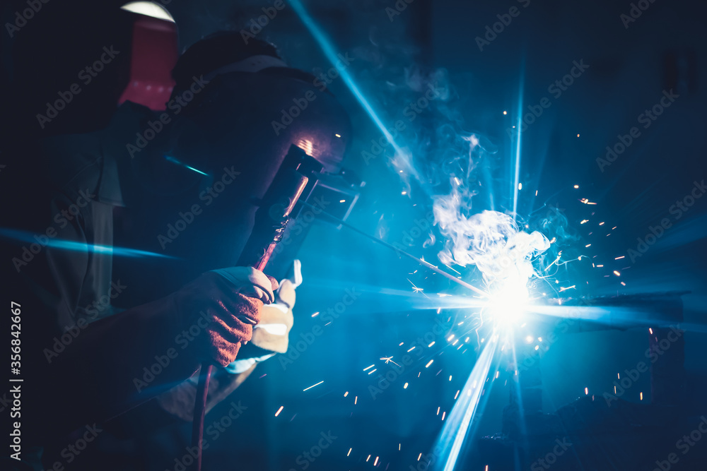 Metal welding steel works using electric arc welding machine to weld steel at factory. Metalwork man