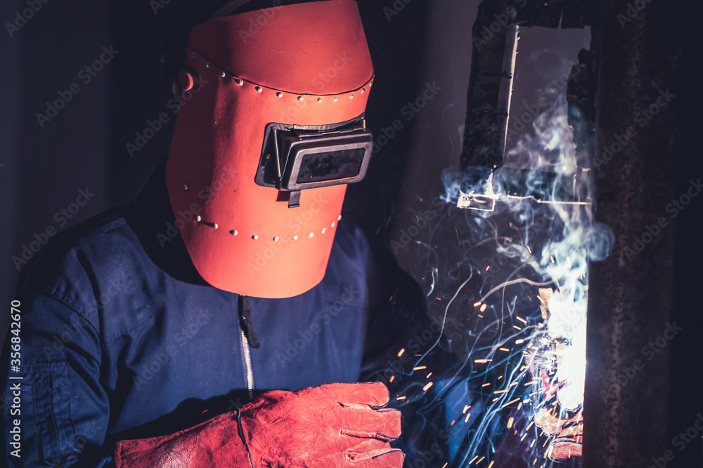 Metal welding steel works using electric arc welding machine to weld steel at factory. Metalwork man