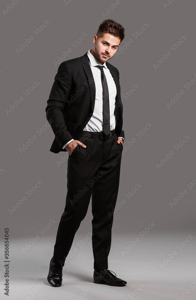 Handsome young man in elegant suit on grey background