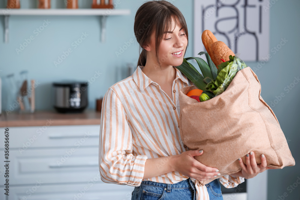 Young woman with fresh products from market at home