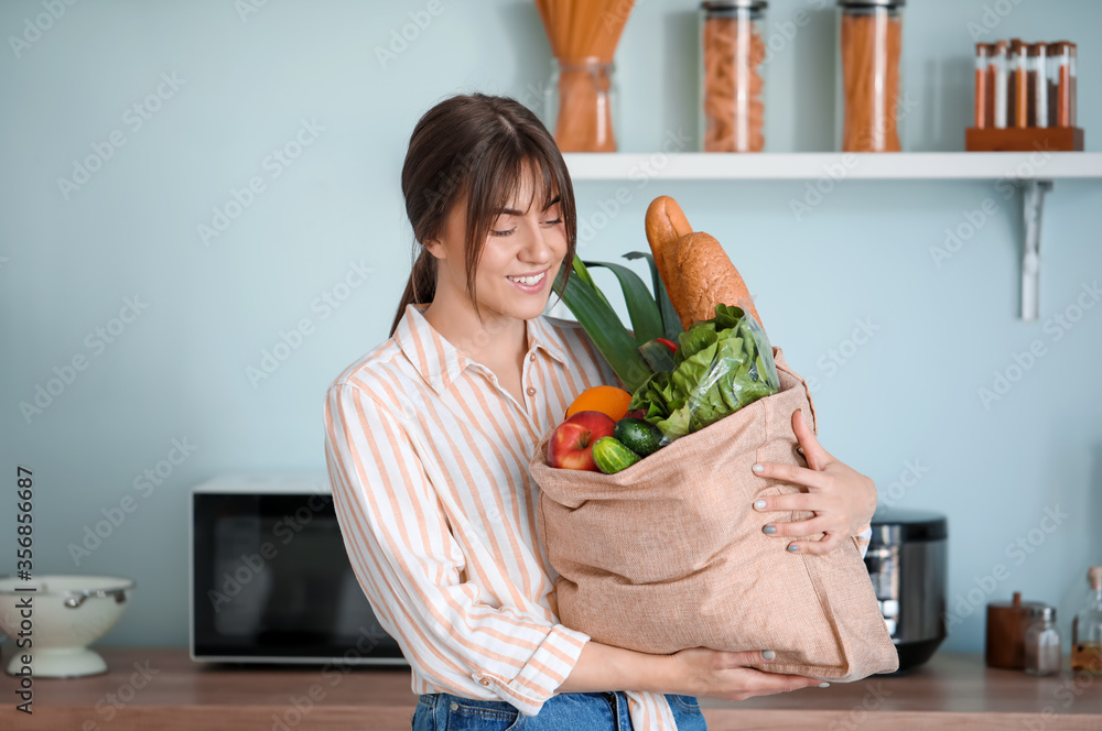 Young woman with fresh products from market at home