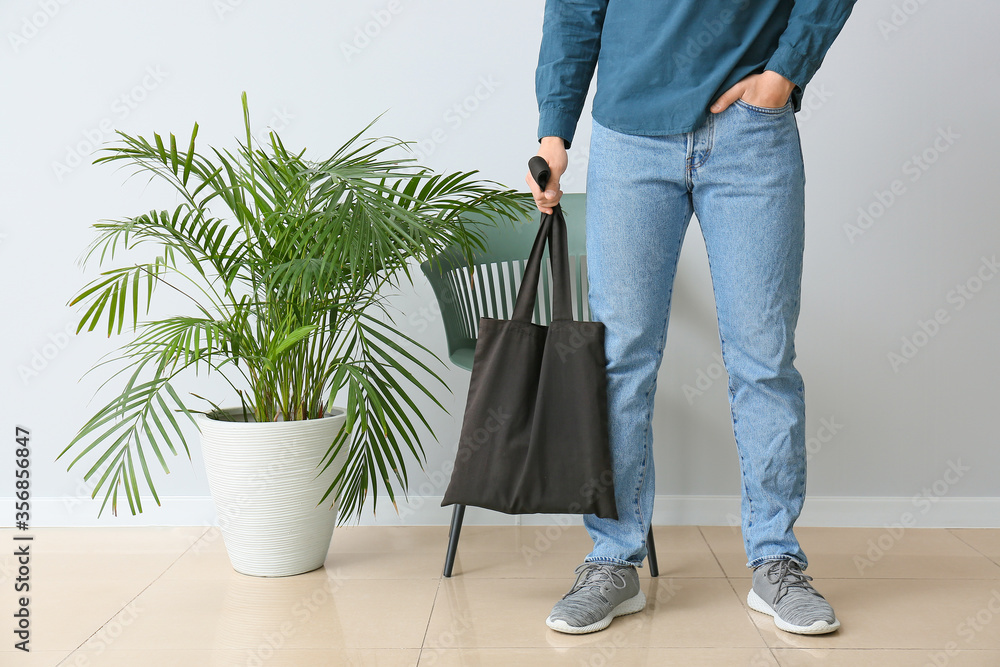 Young man with eco bag against light wall