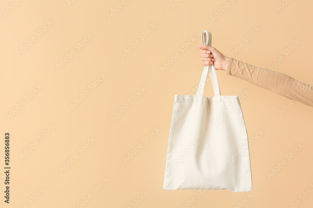 Female hand with eco bag on color background