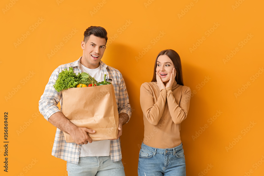 Couple with food in bag on color background