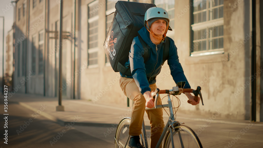 Happy Food Delivery Courier Wearing Thermal Backpack Rides a Bike on the Road To Deliver Orders for 