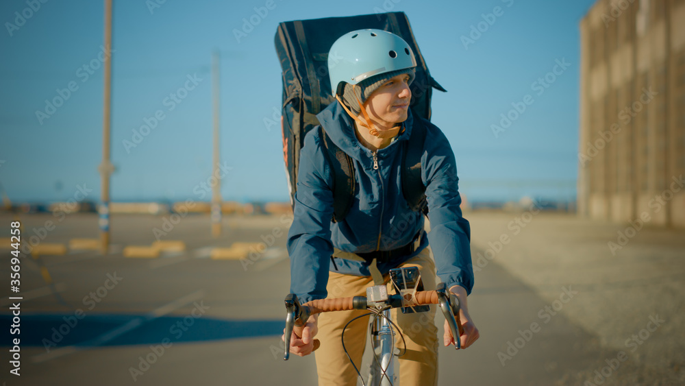 Happy Food Delivery Courier Wearing Thermal Backpack Rides a Bike on the Road To Deliver Orders for 