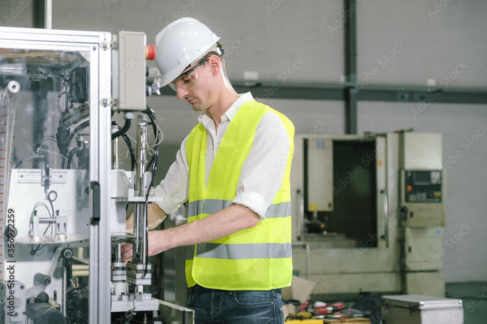 Metal worker teaching trainee on machine use