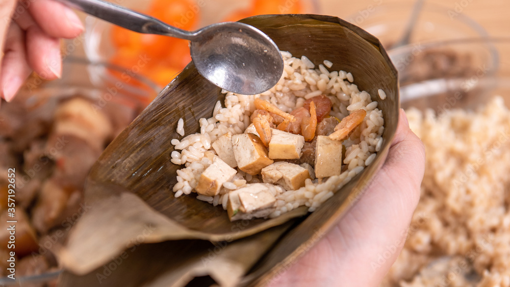 Making Rice dumpling - wrapping Chinese zongzi food on table at home for Dragon Boat Festival celebr