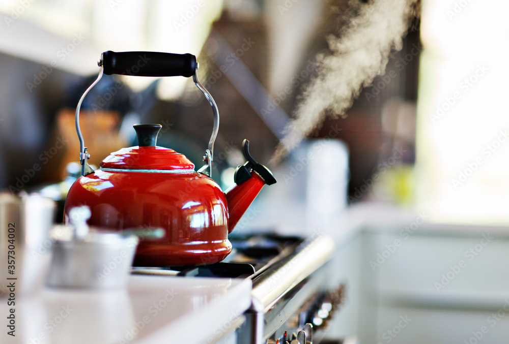 Red old fashion kettle on cooker with steam coming out