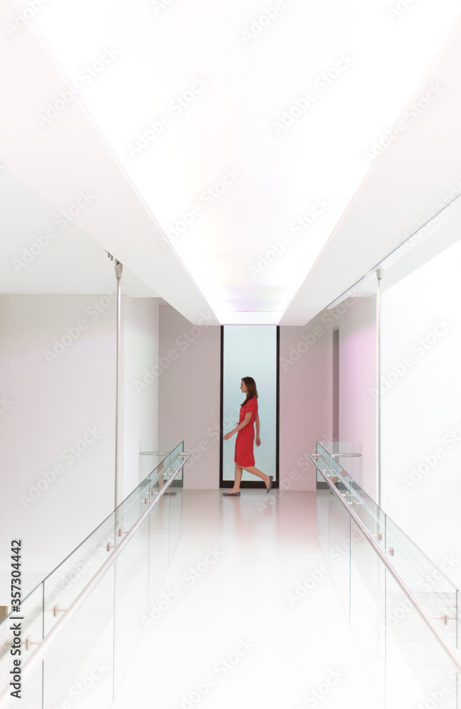 Woman in red dress walking through white modern corridor