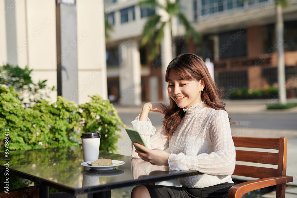 亚洲年轻美女在咖啡馆用手机阅读短信的特写