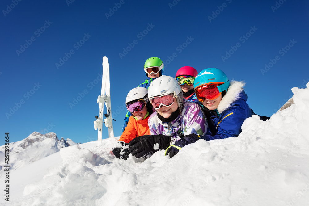 Ski class group of children lay in the snow together in the mountain and have fun, smiling looking a