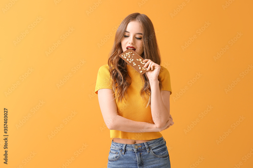 Beautiful young woman with tasty chocolate on color background